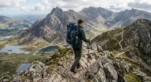 A walker navigating a rocky ridge path in Eryri National Park, Wales, carrying a durable 55l rucksack.