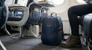 Foldable travel backpack placed under an aeroplane seat as airline approved cabin hand luggage
