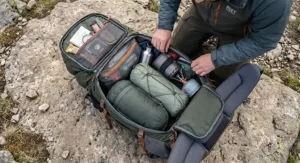 An overhead view demonstrating how to pack a 70l rucksack for hiking, with sleeping bag, stove, and tent arranged efficiently.