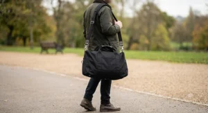 A person comfortably carrying a black lightweight holdall using the detachable padded shoulder strap