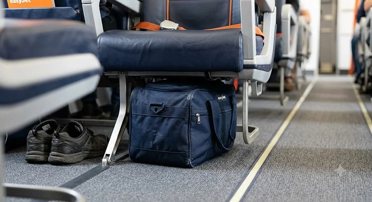 A small underseat bag for easyJet stowed neatly beneath the seat in front on a flight.