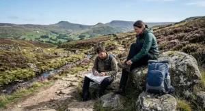 Walkers resting with a lightweight waterproof daypack beside a trail in the Peak District National Park.