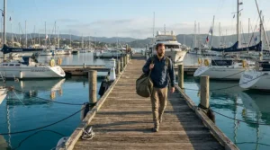 Carrying a heavy-duty waterproof holdall for sailing along a wooden pontoon in Cornwall.
